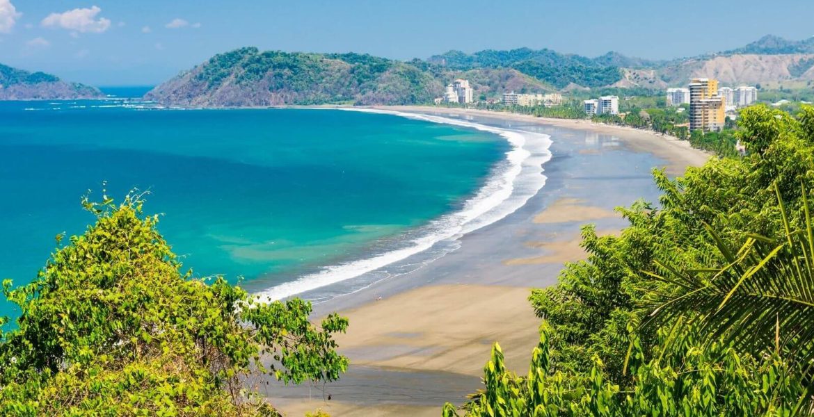 Scenic view of Jaco Beach framed by tropical foliage, ideal photo stop on a Private Costa Rica airport transportation service