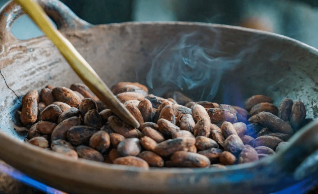 Roasted cacao beans in a hot pan releasing steam — chocolate tour in La Fortuna, Costa Rica